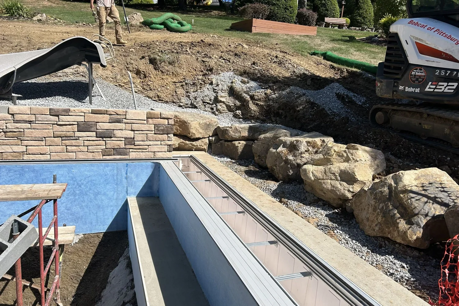 The raised wall rising along the pool in block and stone veneer