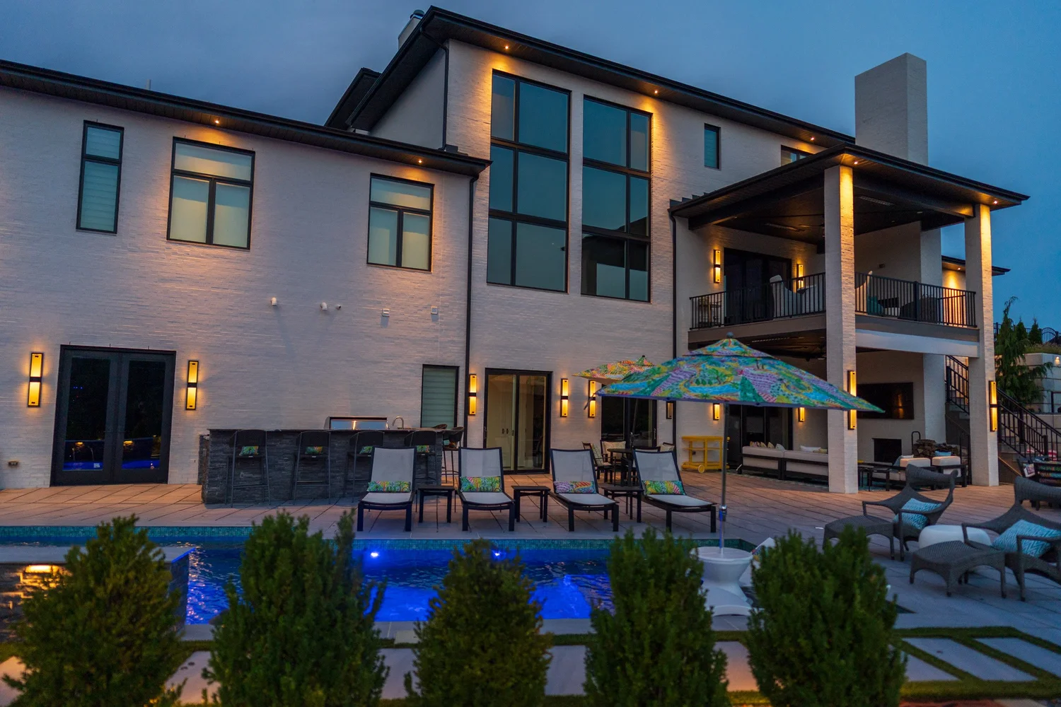 The back of the house, the covered porch and the pool at dusk