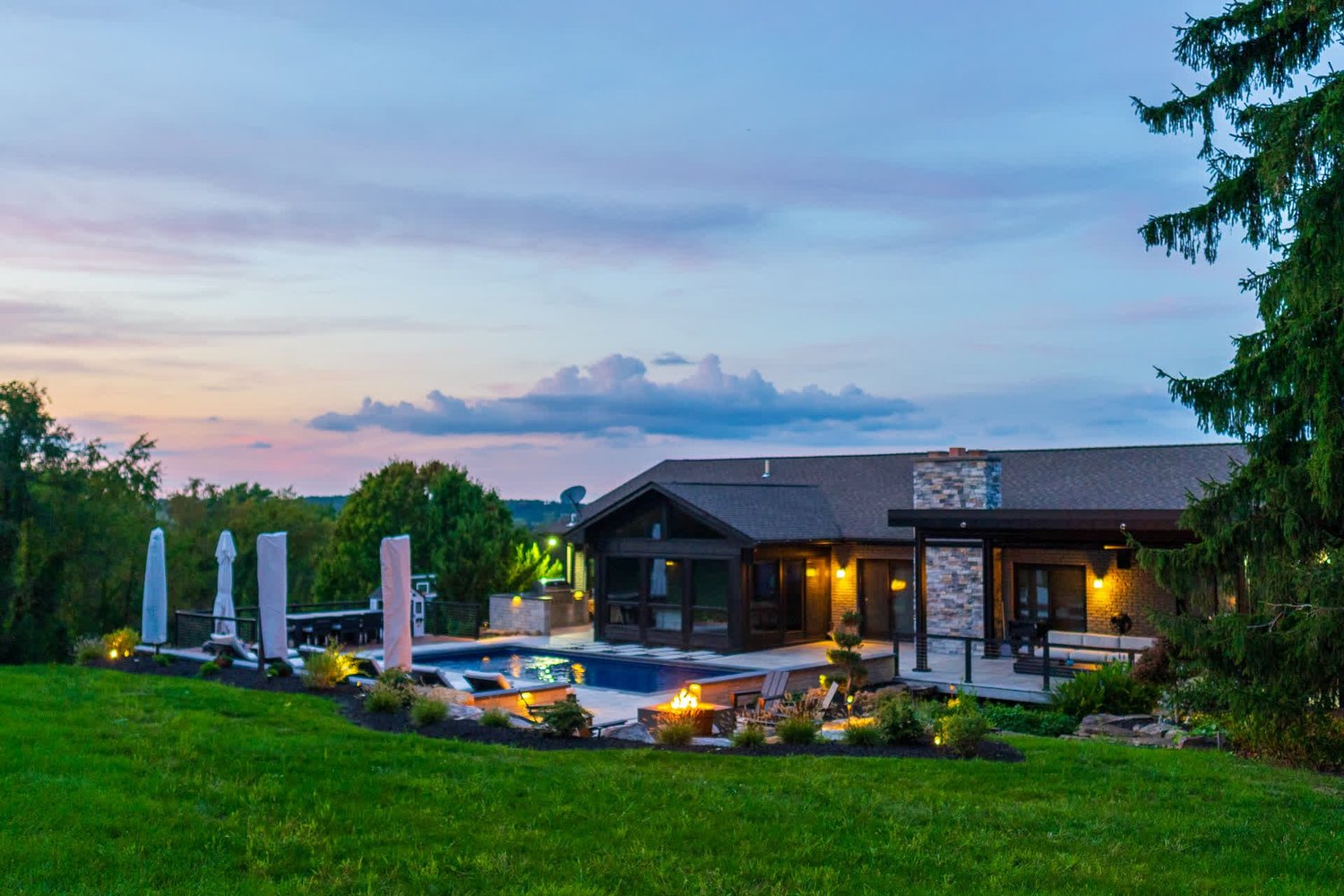 A house, a pool and a wide lawn at dusk