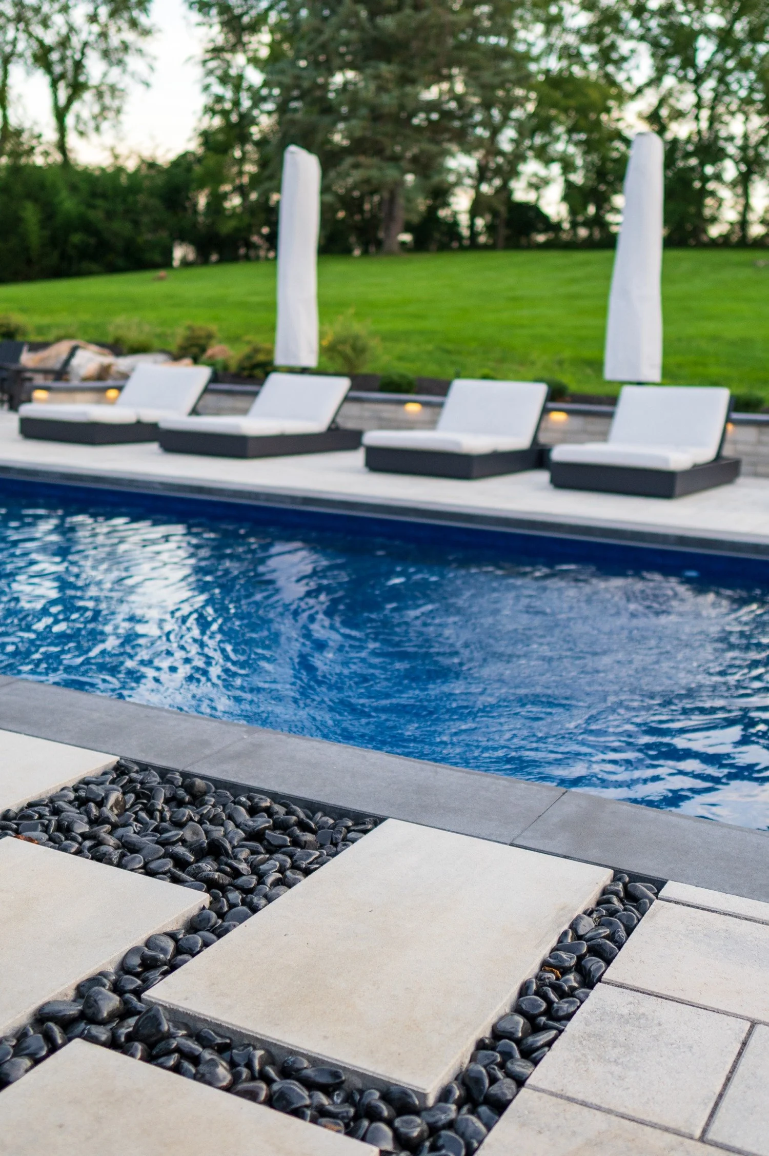 Loungers along the pool and step pavers in black river rock