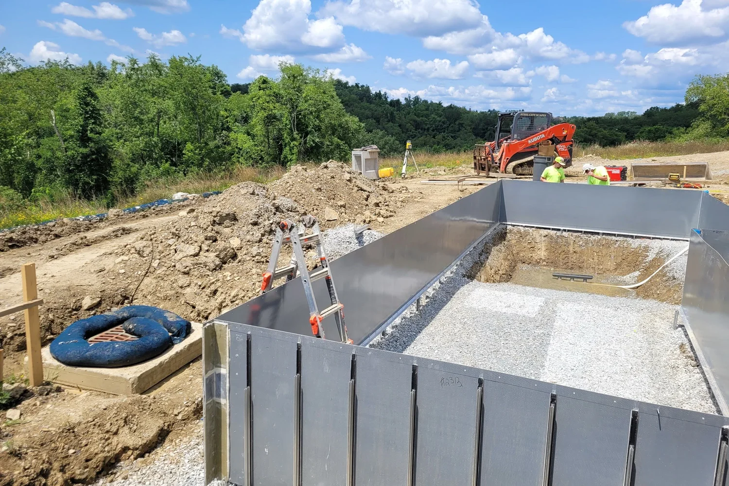 The steel pool walls set in the dig, with the valley beyond