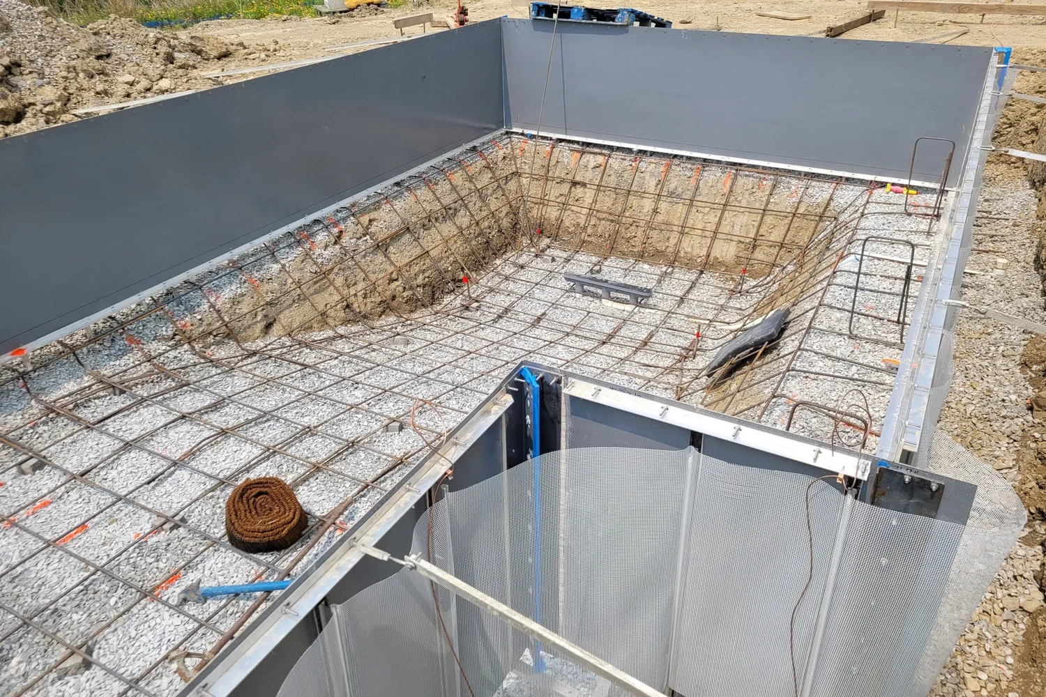 Rebar laid across the pool floor inside the steel walls