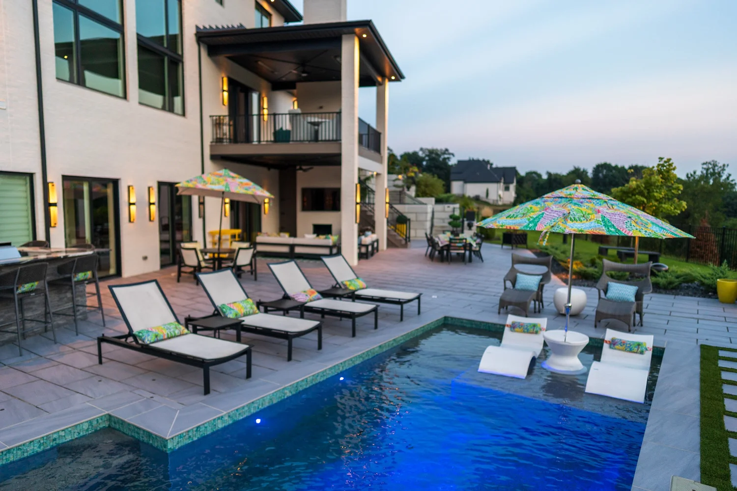 The pool, the sun shelf and the deck along the back of the house at dusk
