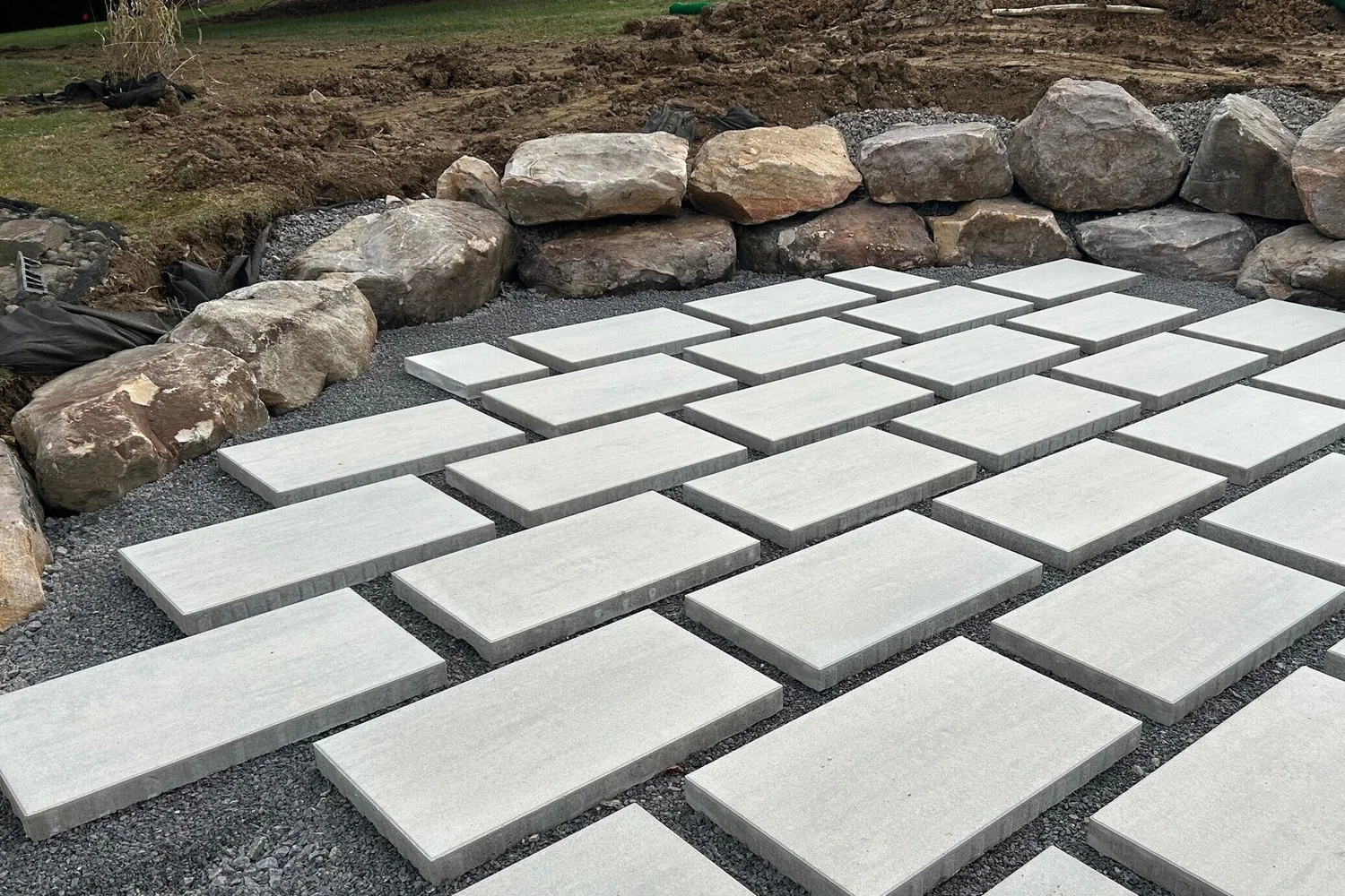 Patio base and pavers against a boulder wall