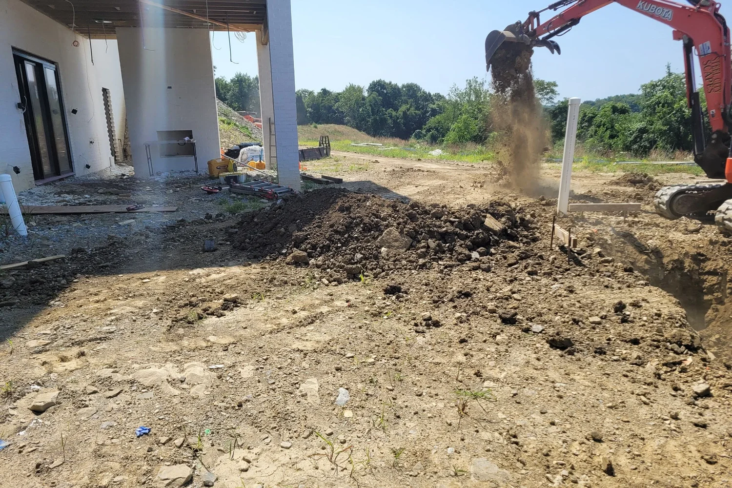 An excavator digging the pool beside the new house