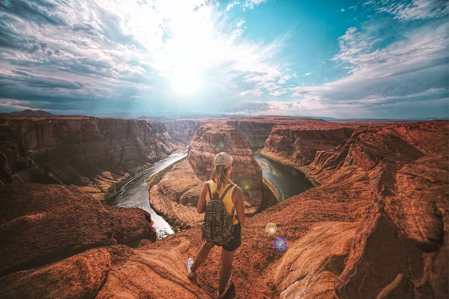 Person overlooking a scenic vista of a canyon with water flowing through it.