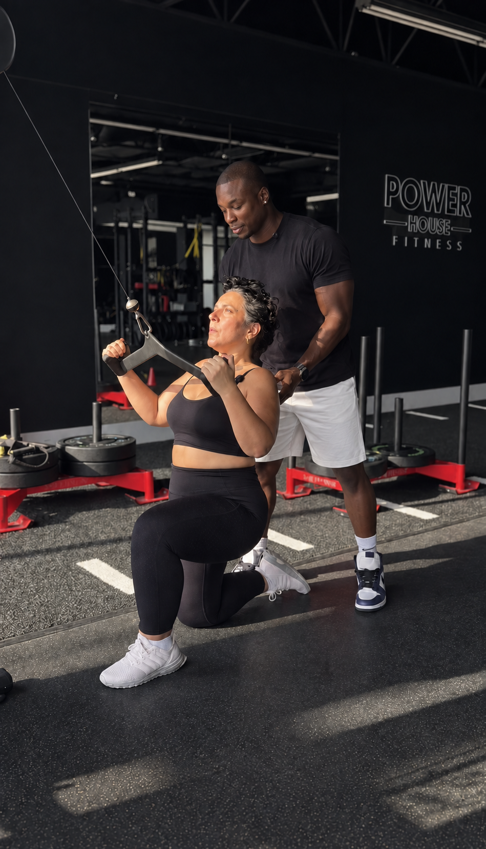 Dushane coaching a client during a cable exercise at Power House Fitness