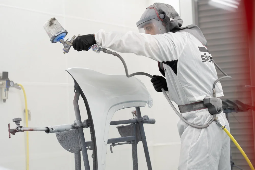 Painter spraying a panel in the booth
