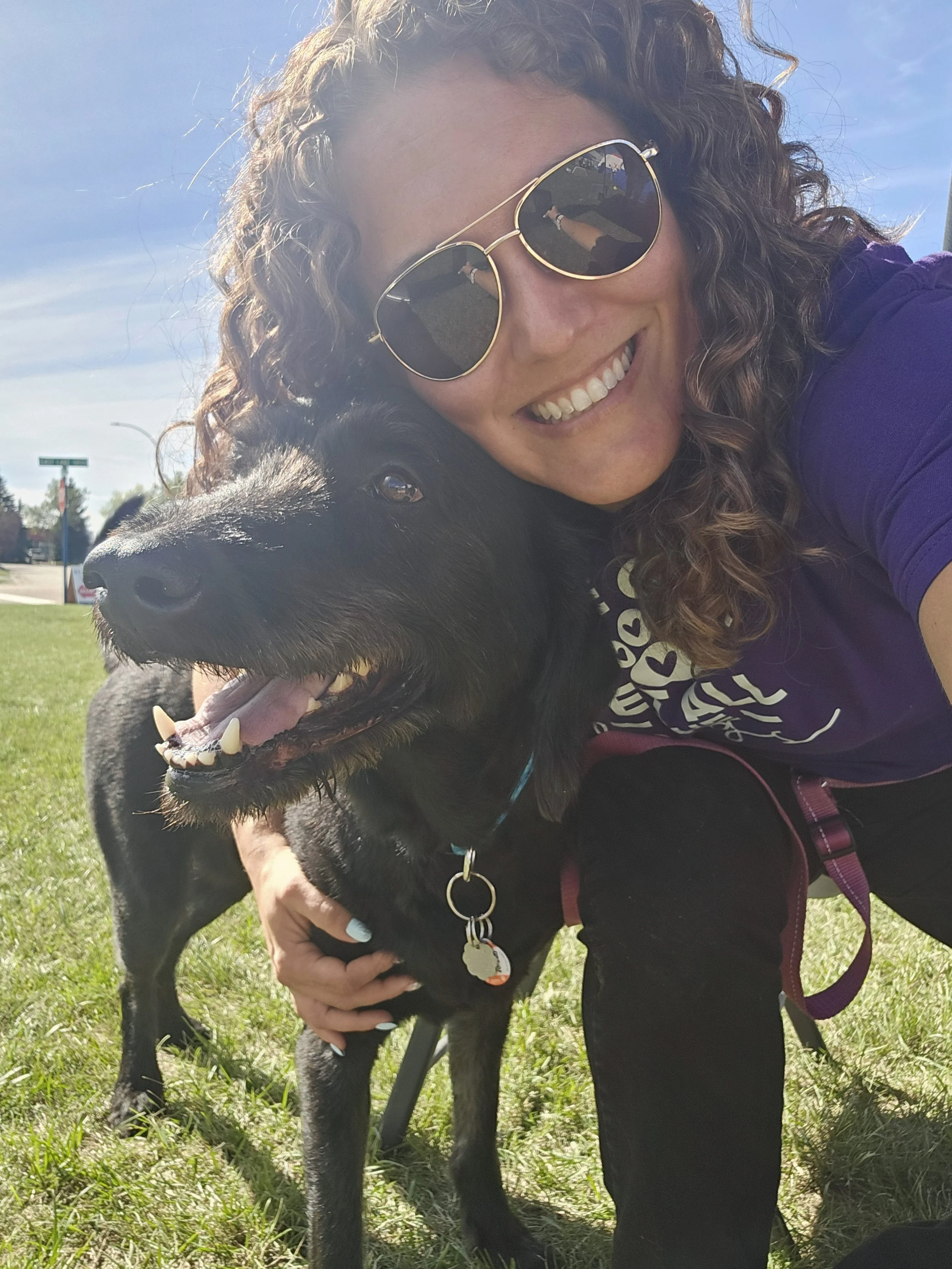 Nikki Nordick smiling with a happy black dog outdoors