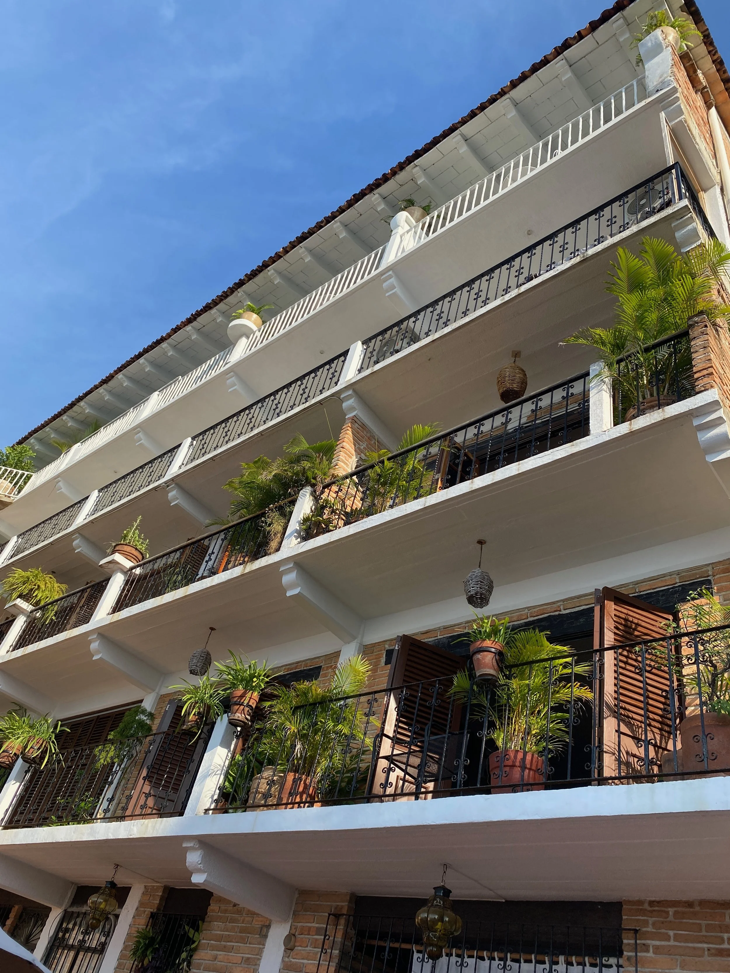 Stacked white balconies with wrought-iron railings and hanging lanterns, traditional colonial architecture in Puerto Vallarta