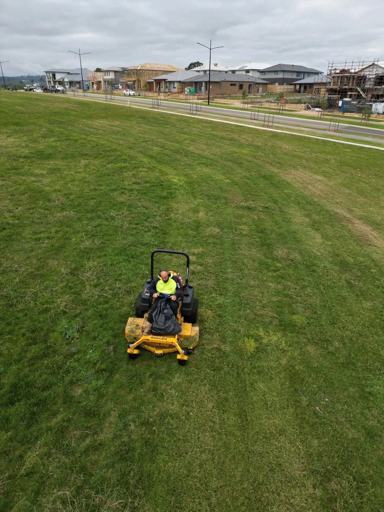 Operator on a ride-on mower cutting estate open space