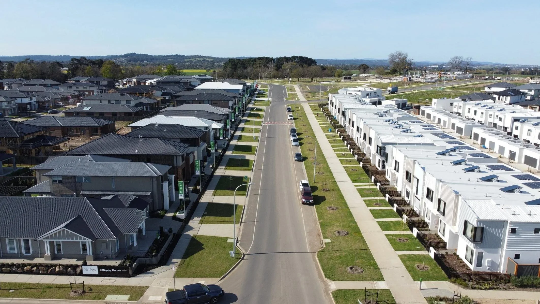 Drone view of an estate street with new homes, nature strips and street trees