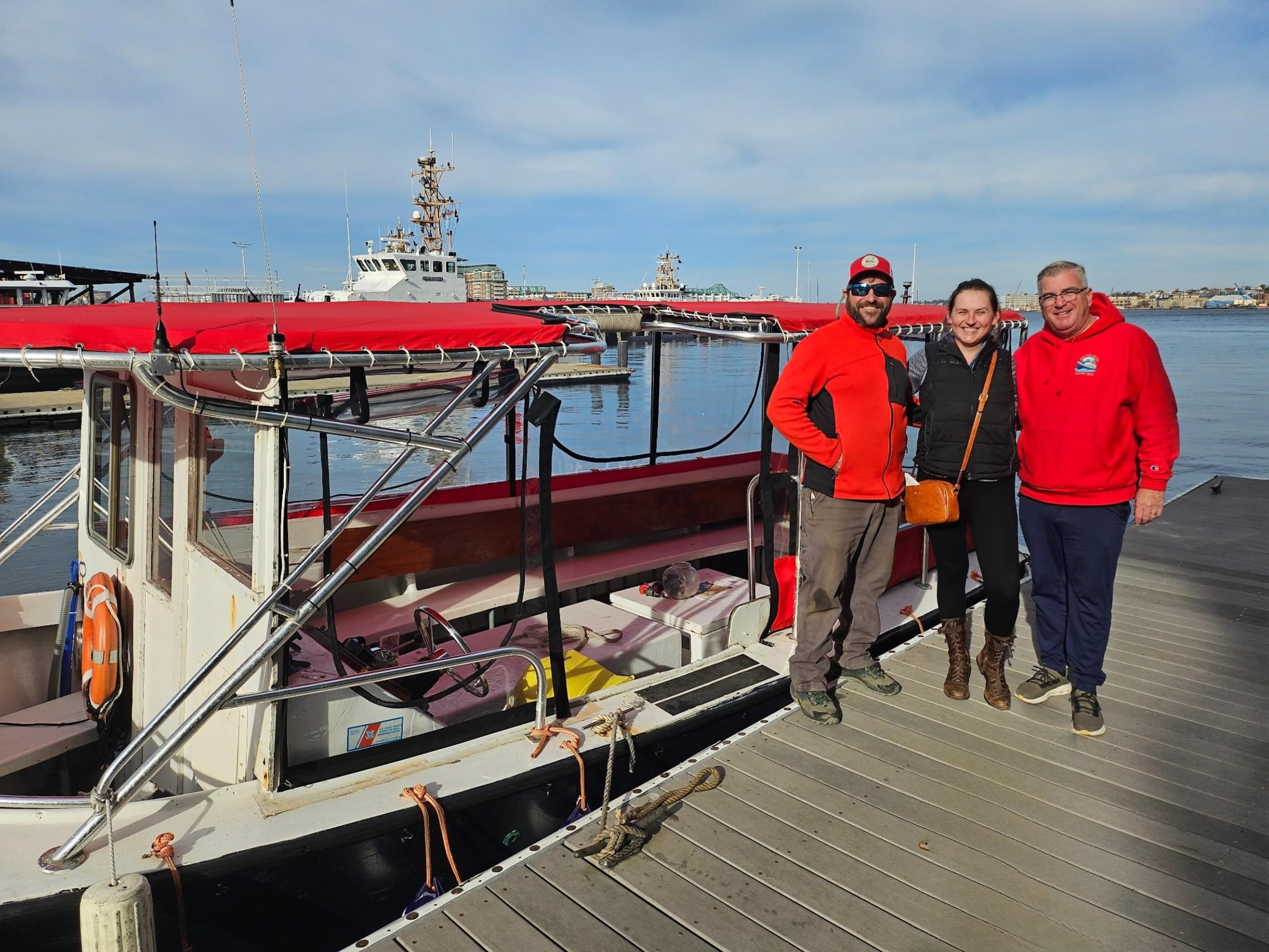 Three people in front of a Red Top Boat
