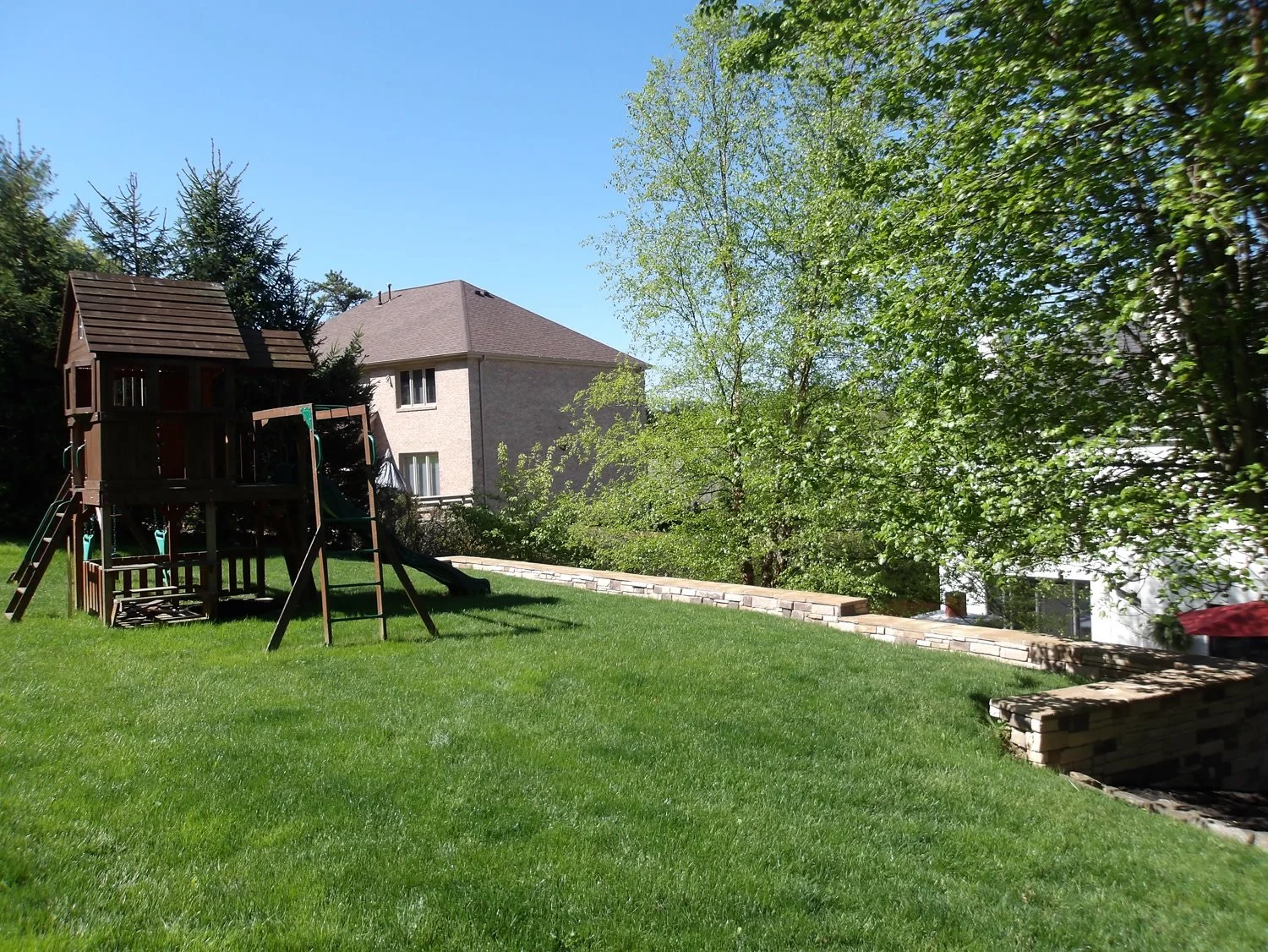 A sloped rear lawn with a wooden play set before the project
