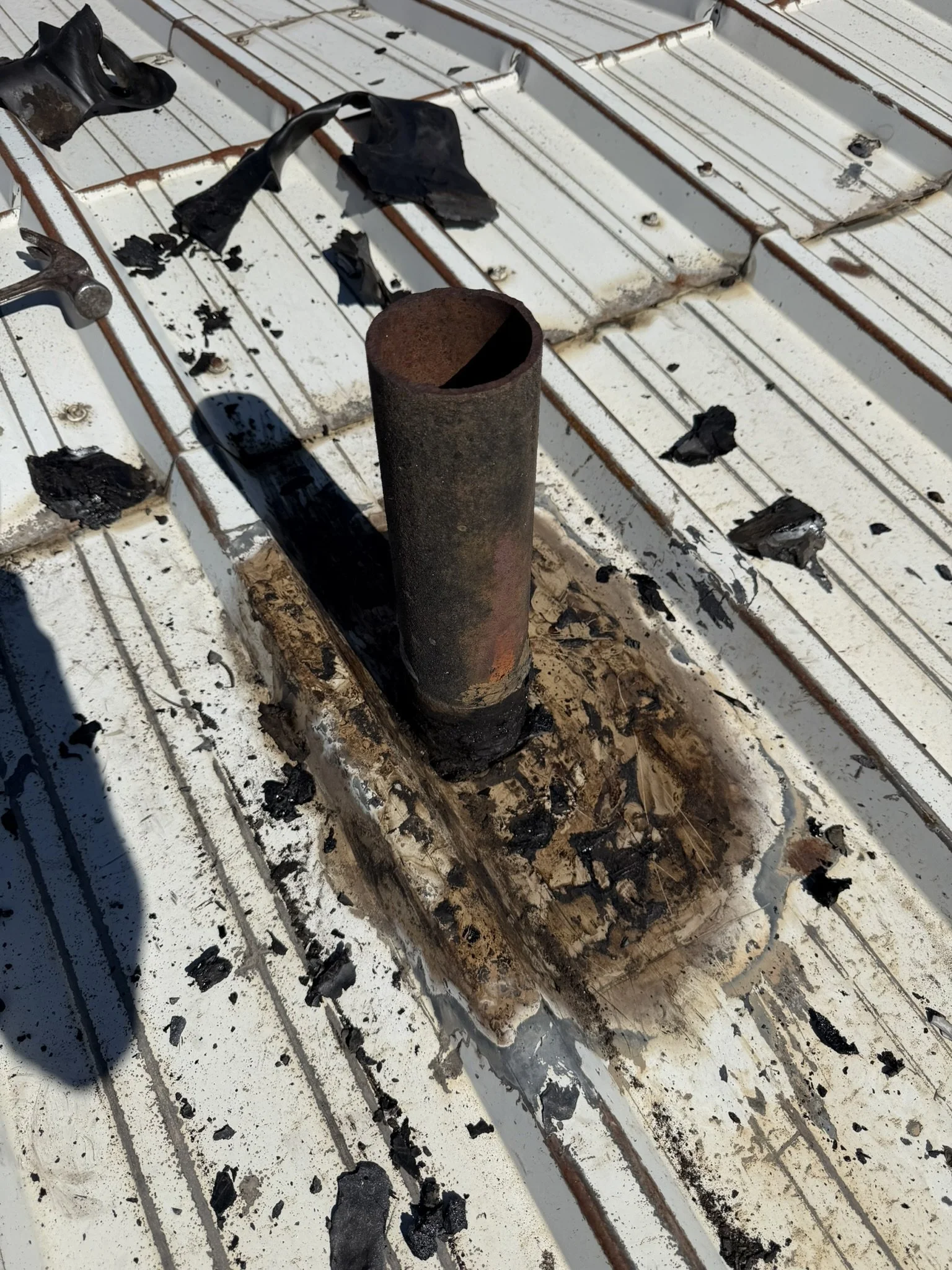 Metal roof around a pipe after old sealant buildup was removed.