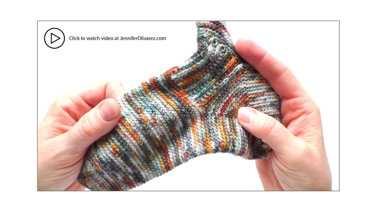 Two hands holding a multicolored crochet sock.