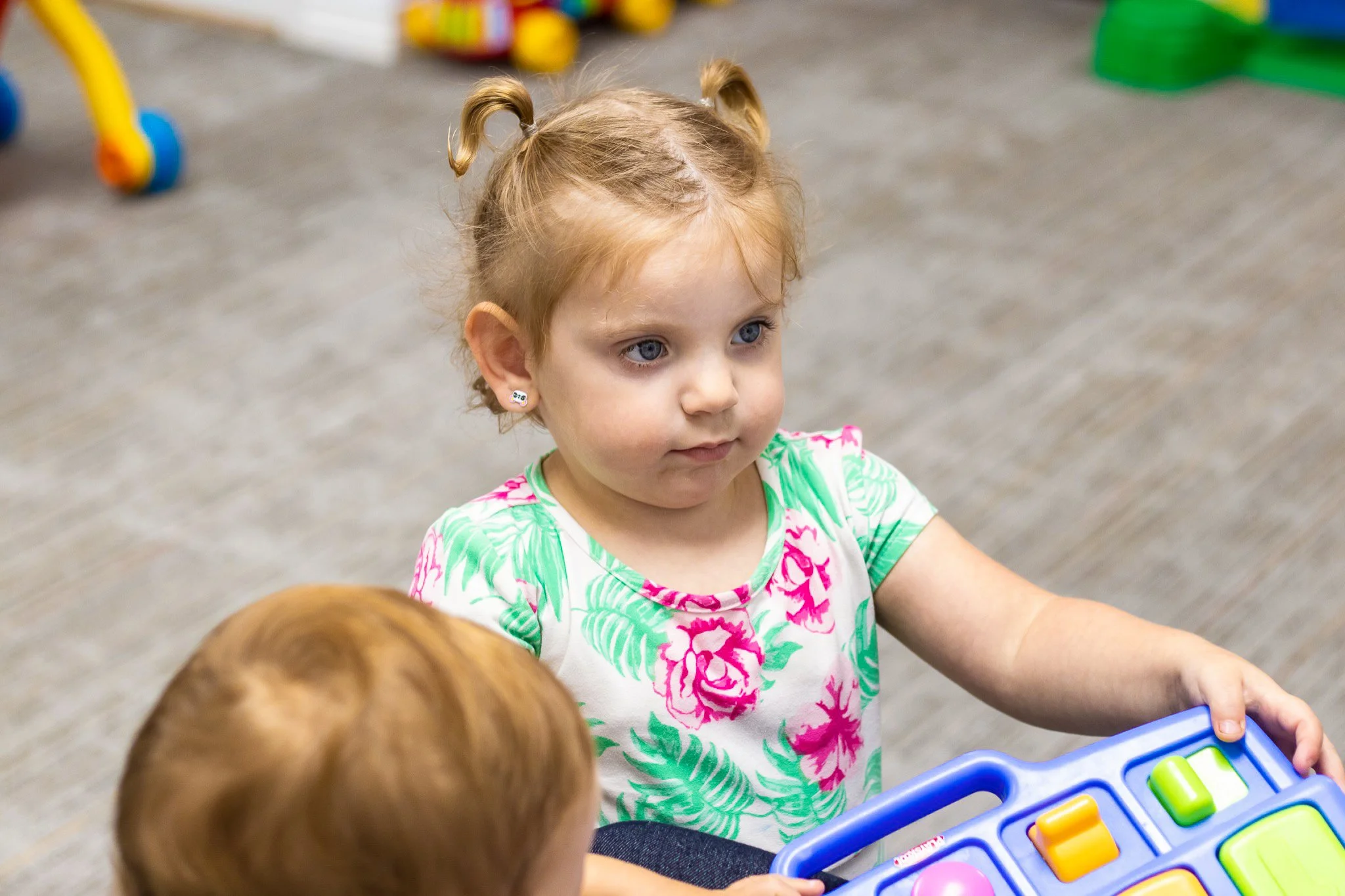 Young child playing with a colorful activity toy in a church nursery.