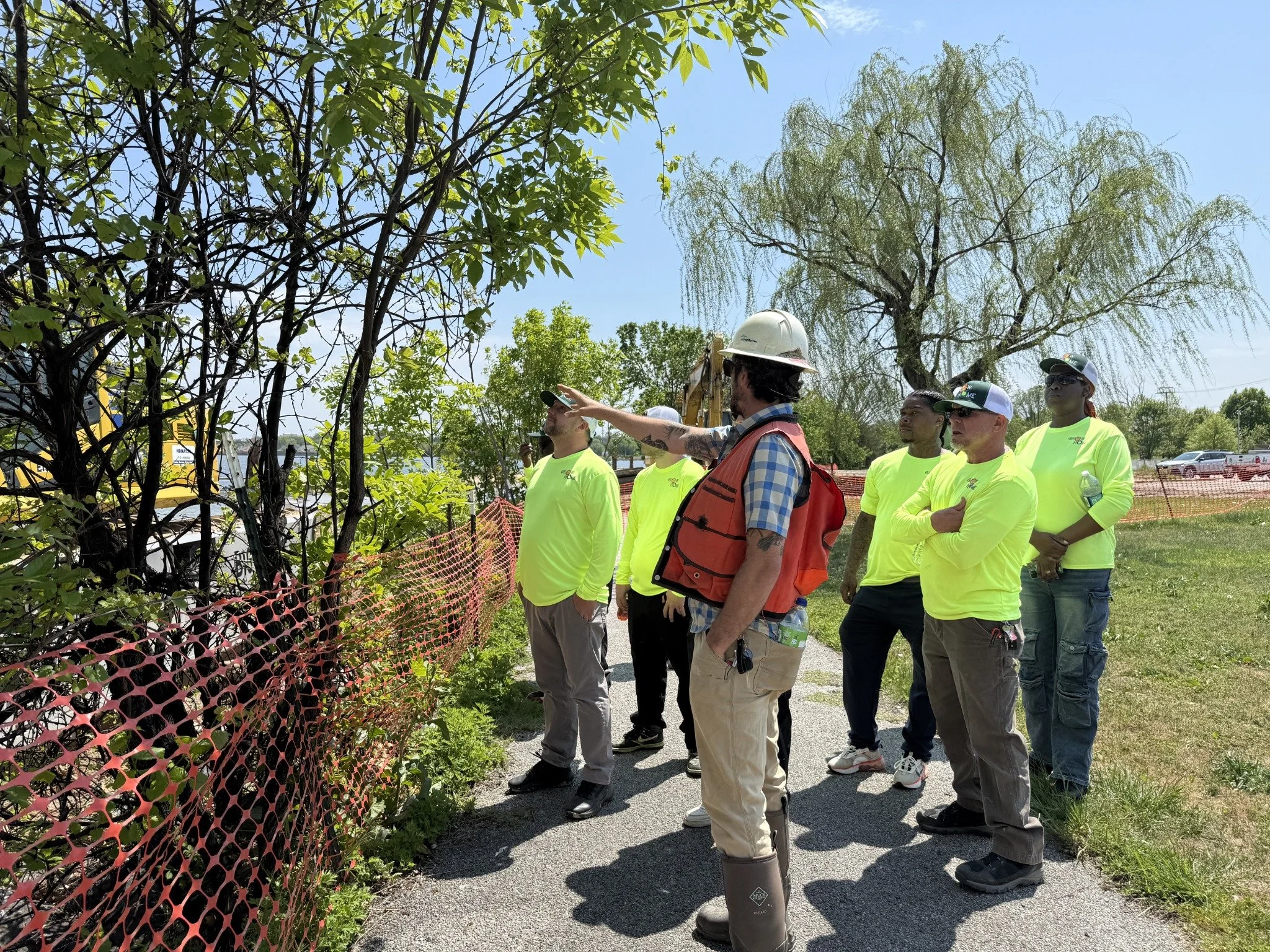 A field instructor and workers discussing trees during an outdoor restoration training session