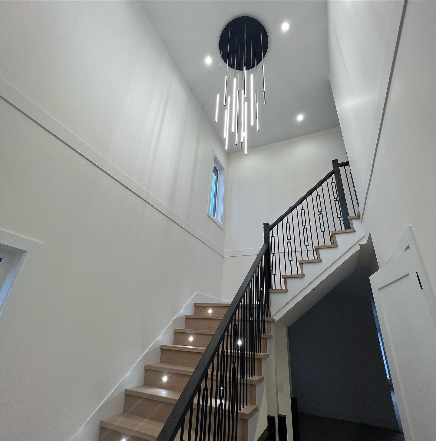Bright North Delta custom home staircase with chandelier and step lighting