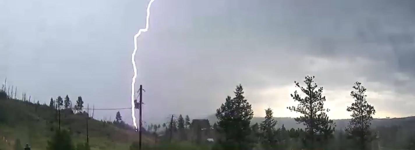 Lightning strikes a mountainside near a power pole
