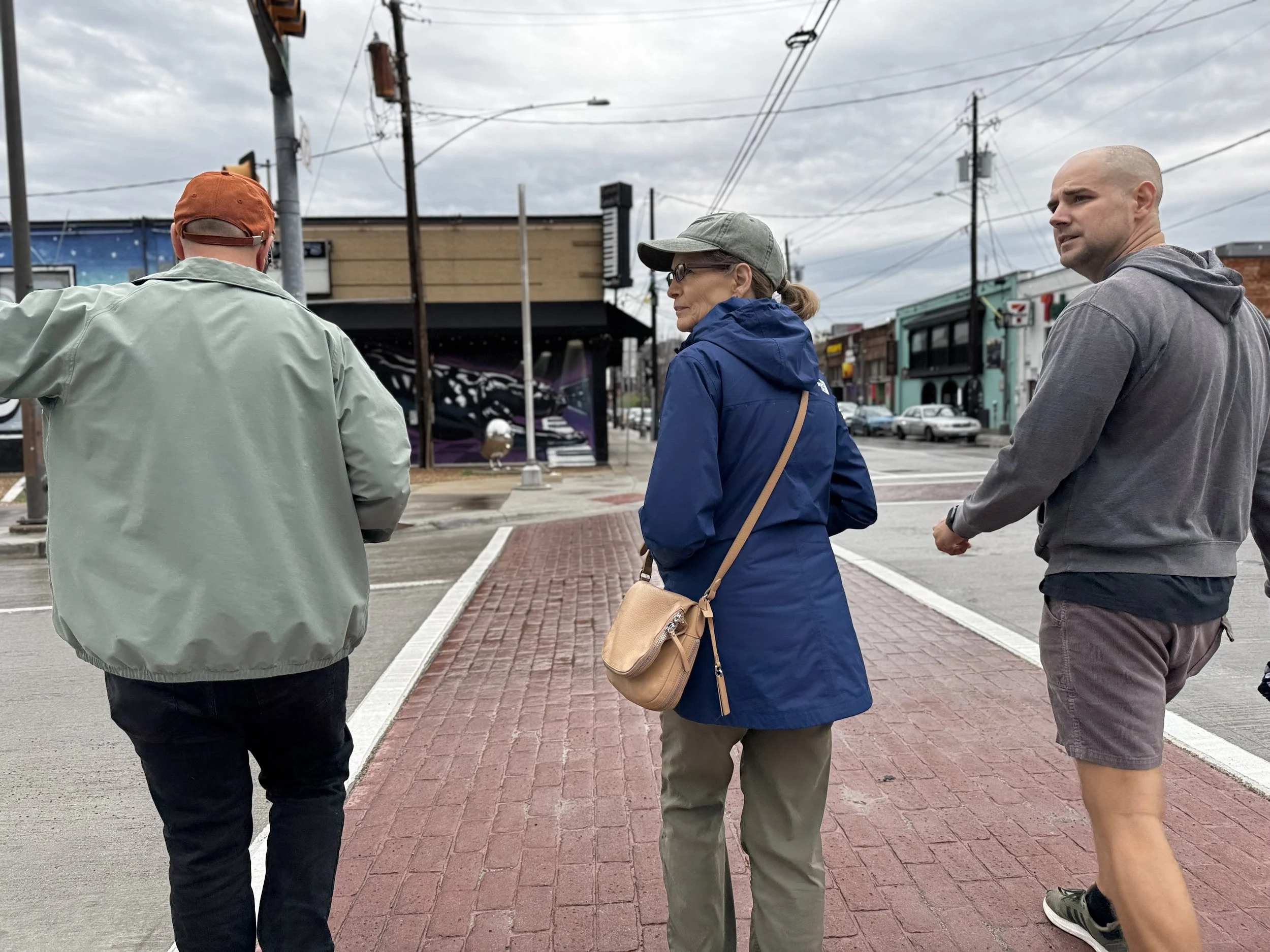 Three people exploring Deep Ellum on foot at a neighborhood crosswalk.