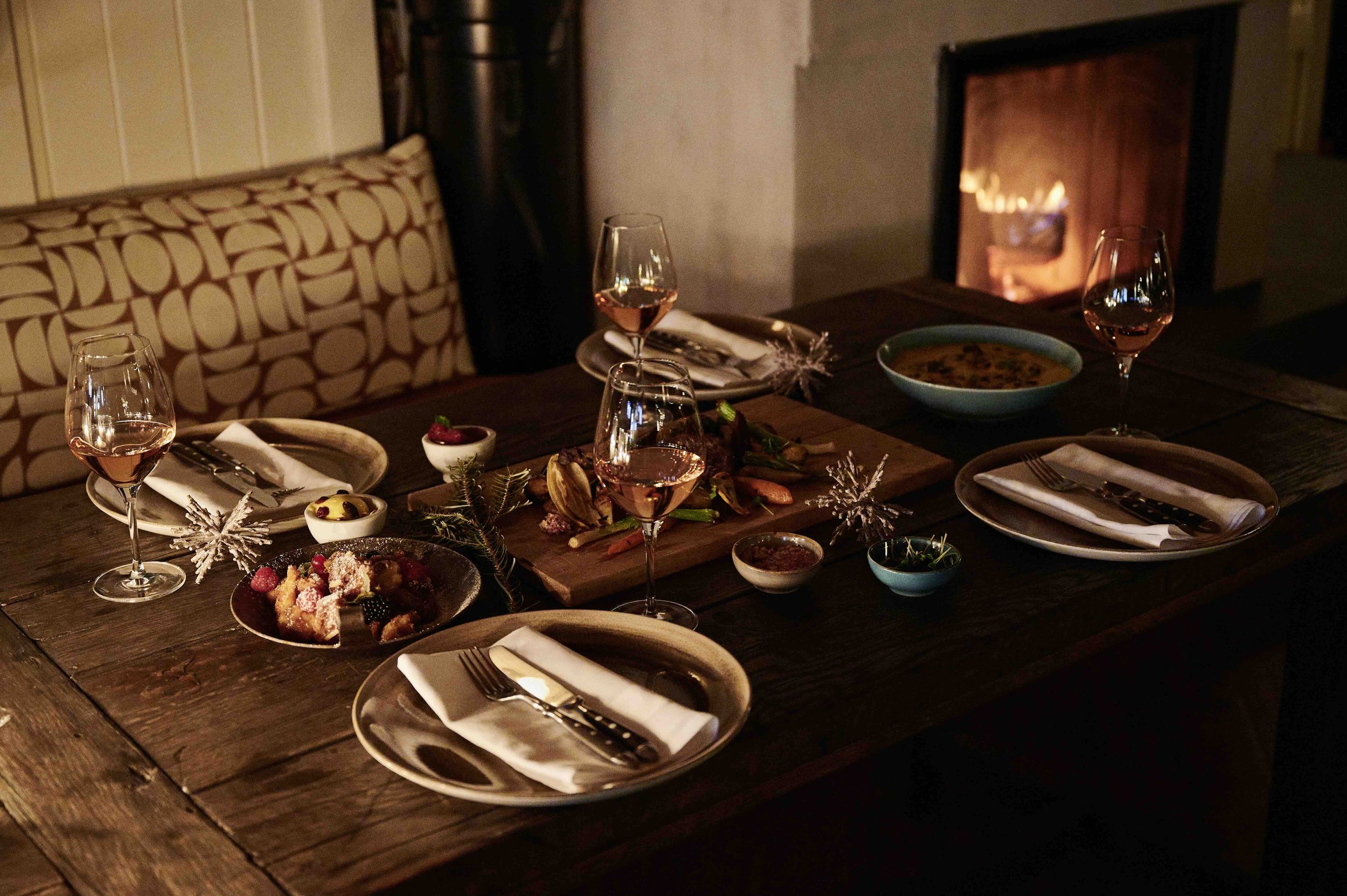 Weihnachtlich gedeckter Tisch mit Wein vor dem Kamin