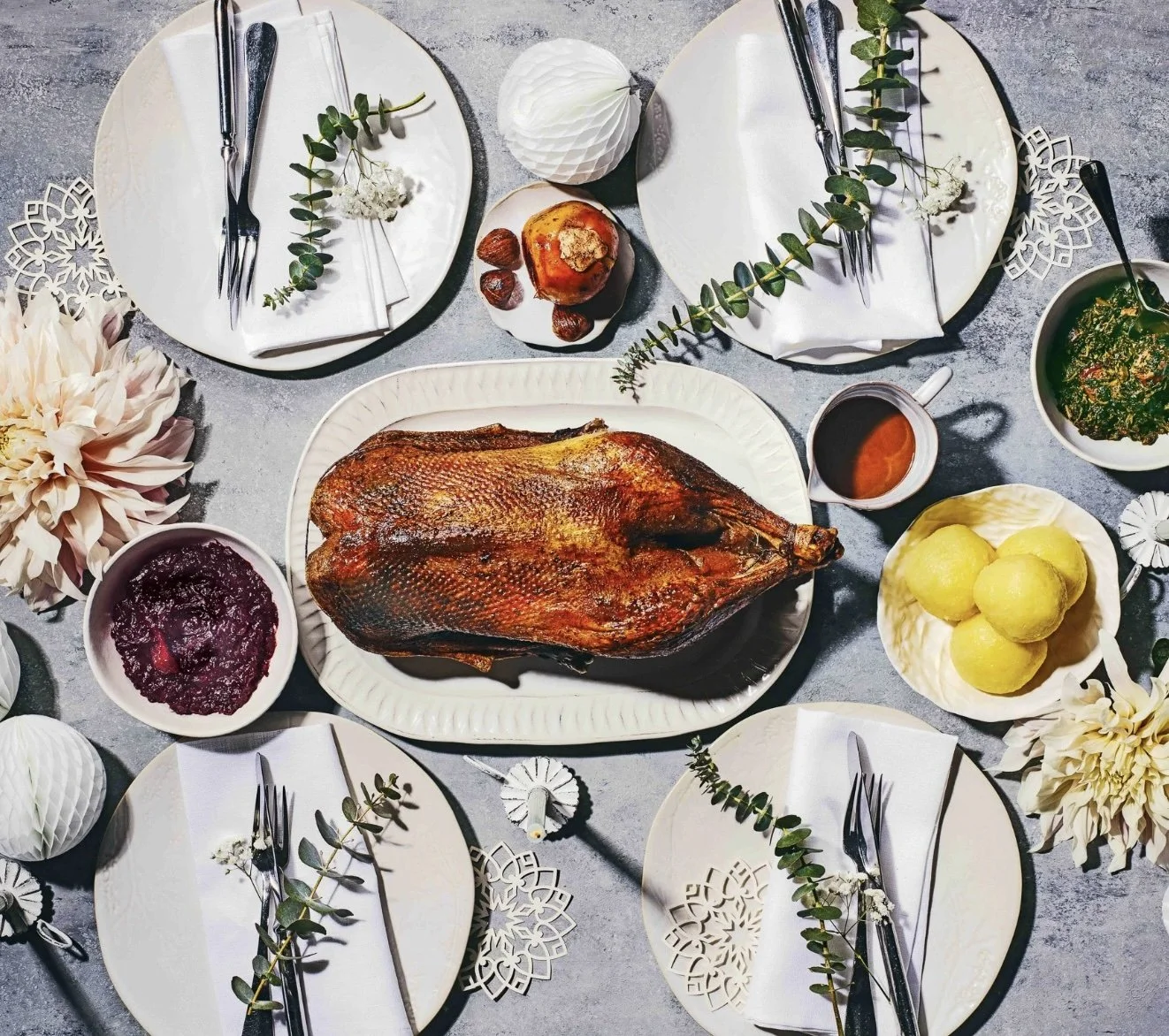 Ganze Freilandgans mit Rotkohl, Grünkohl, Klößen und Jus auf festlich gedecktem Tisch