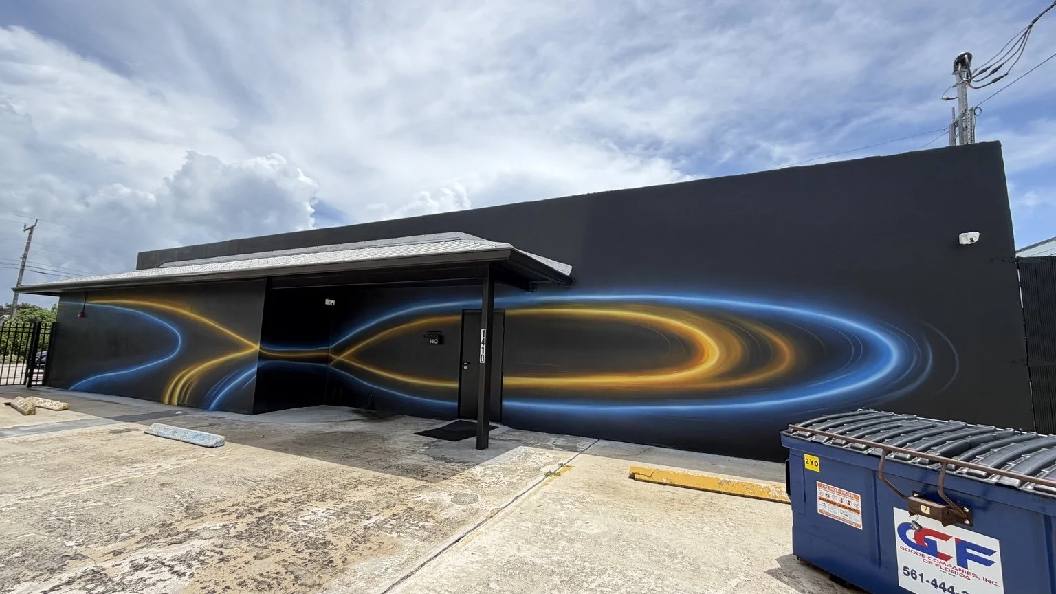 Looping blue and gold light trails painted around the entrance of a black commercial building