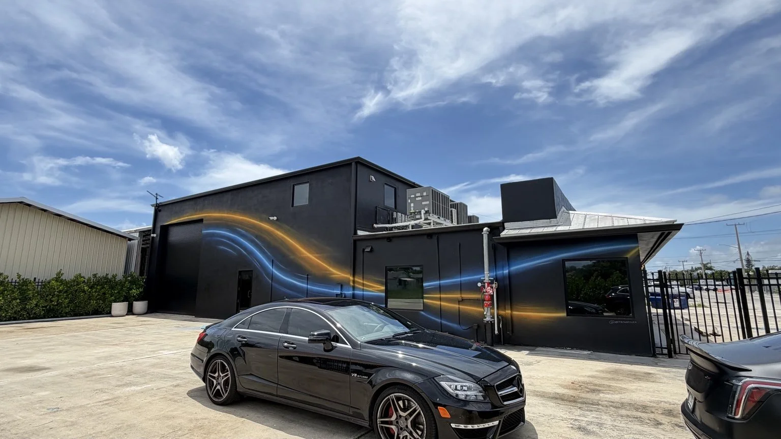 Wide view of the completed blue and amber abstract building mural wrapping around the exterior