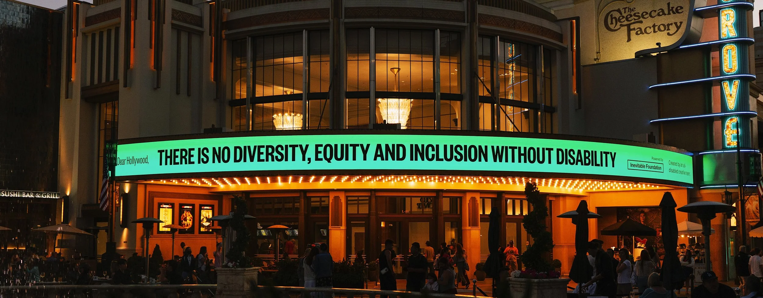 A photograph of a night scene with a venue marquee displaying a message about diversity and inclusion.