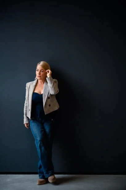 Founder in a tailored jacket against a dark wall, brand photography by Tanja Pleis
