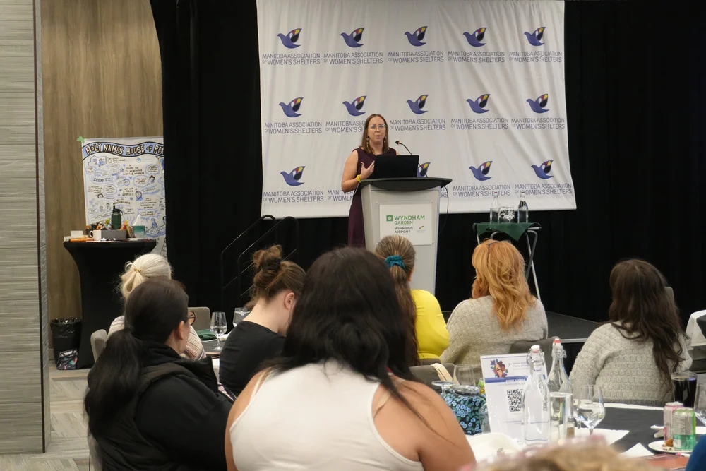 Monica speaking to a full room at the Gender-Based Violence Symposium