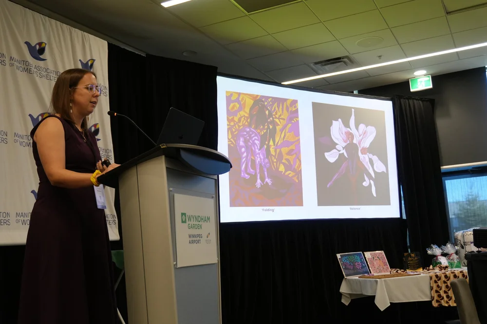 Monica presenting her paintings on stage at the MAWS Gender-Based Violence Symposium in Winnipeg