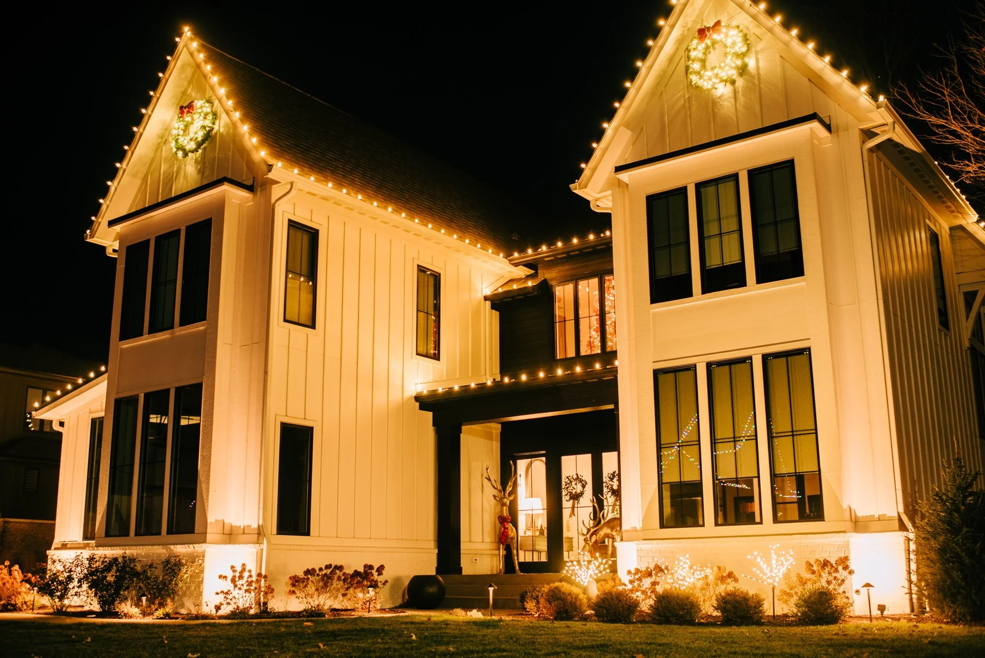 Home with custom warm white holiday lights outlining roof peaks and entryway