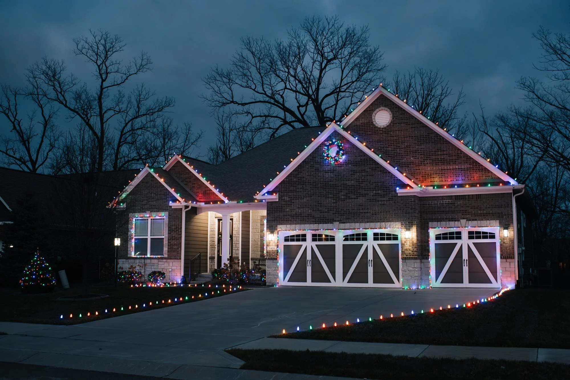 Home with colorful Christmas roofline lights and lights outlining the curved driveway