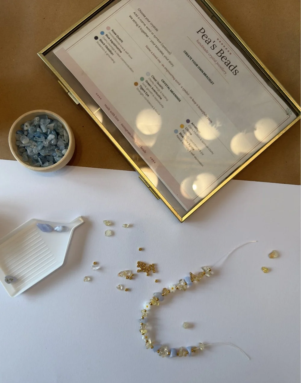 A bracelet-making table with crystal beads and a Pea’s Beads guide