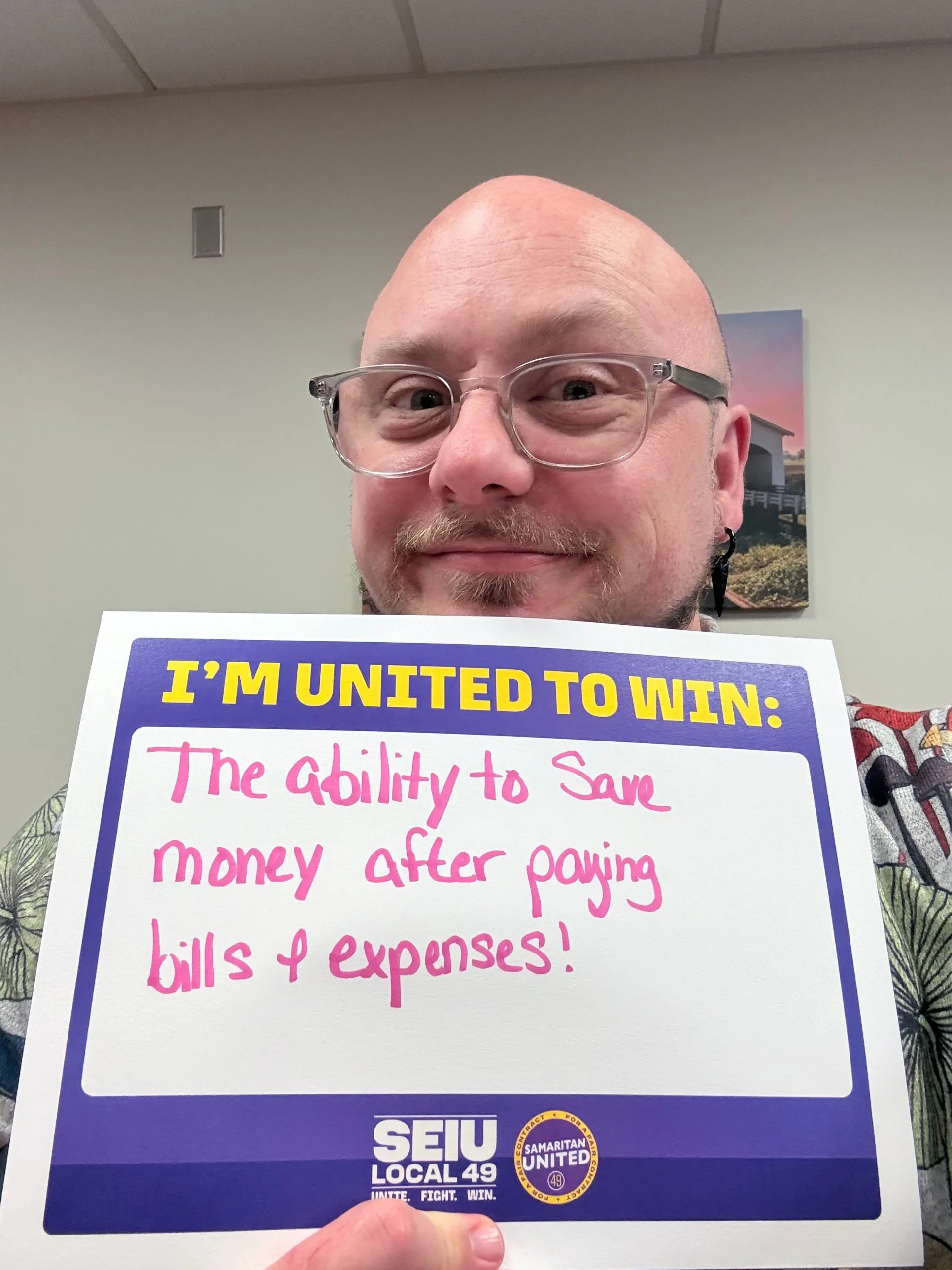 A member holds a sign that reads: “I’m united to win: The ability to save money after paying bills & expenses!”