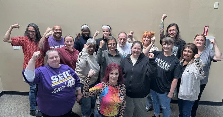 Legacy workers with SEIU 49 raise their fists together.