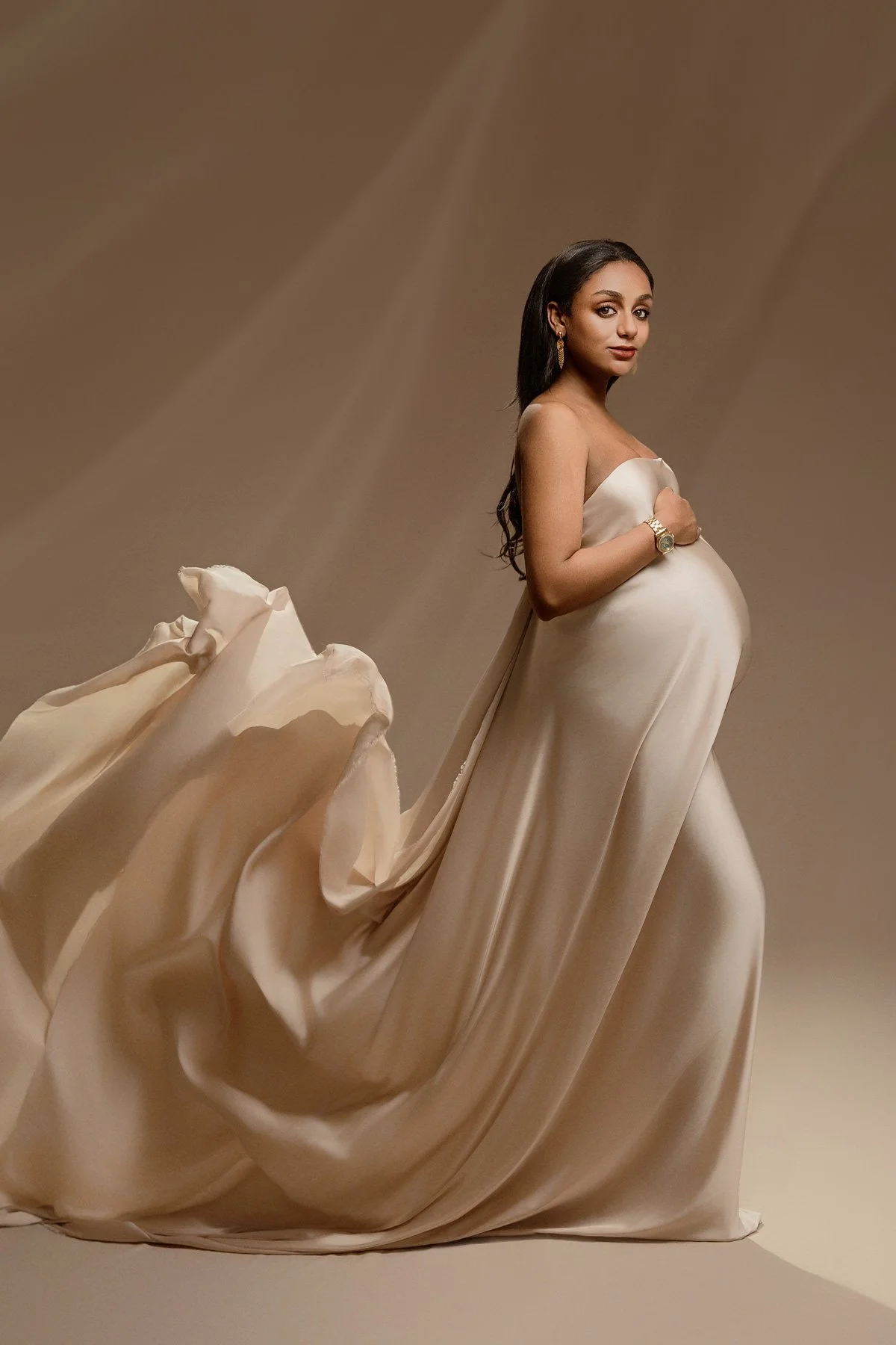 Pregnant woman in a flowing beige silk gown