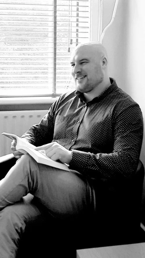 Dr Colm Marren seated and smiling, holding a notebook.