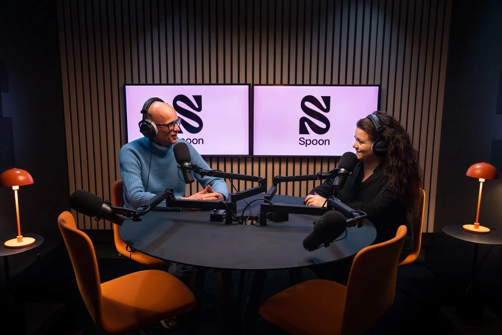 Podcast-studio med to personer som snakker og mikrofoner