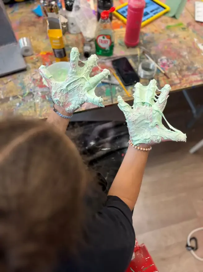 A young person holding out their hands covered in slime