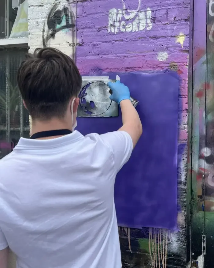 A young person spray painting in our courtyard