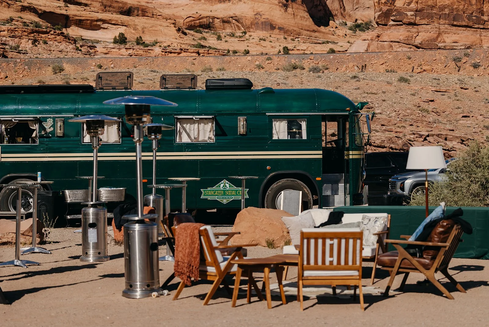 A plush outdoor desert lounge at dusk with a fire pit and string lights
