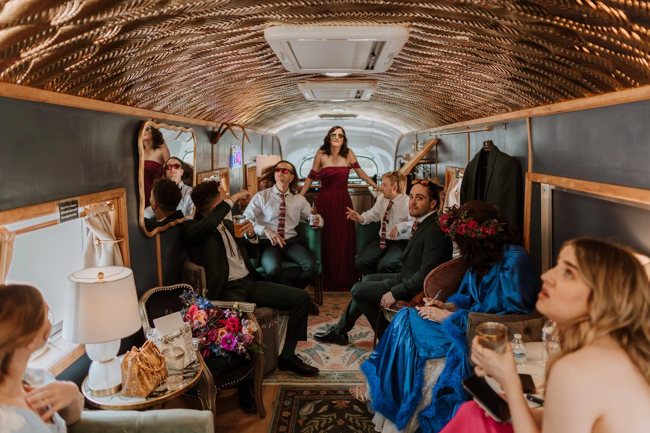 The full wedding party celebrating inside the Stargazer lounge, bridesmaids and groomsmen gathered the length of the bus.