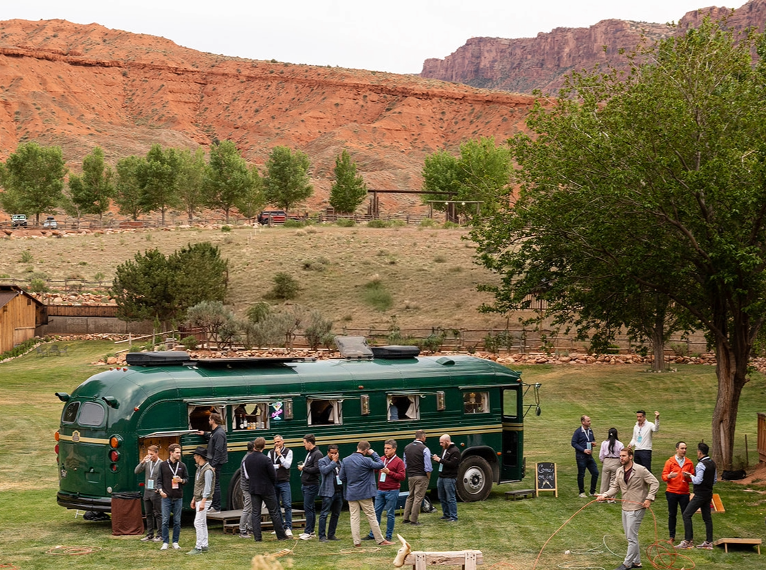Corporate guests in blazers mingling by the bus bar at golden hour