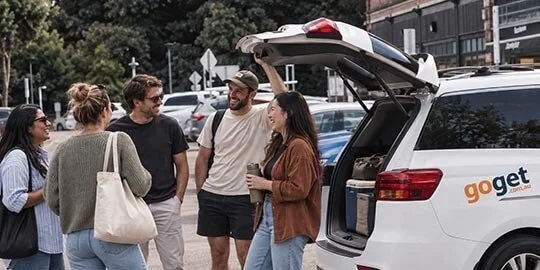 Group of friends loading bags into the boot of a GoGet people mover