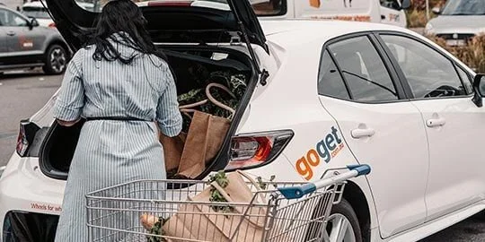 Member loading shopping bags into the boot of a white GoGet car