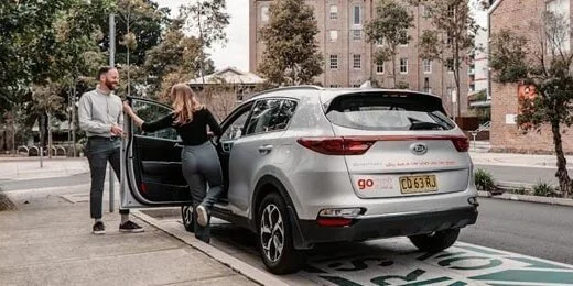 Two members getting into a silver GoGet SUV parked in its pod