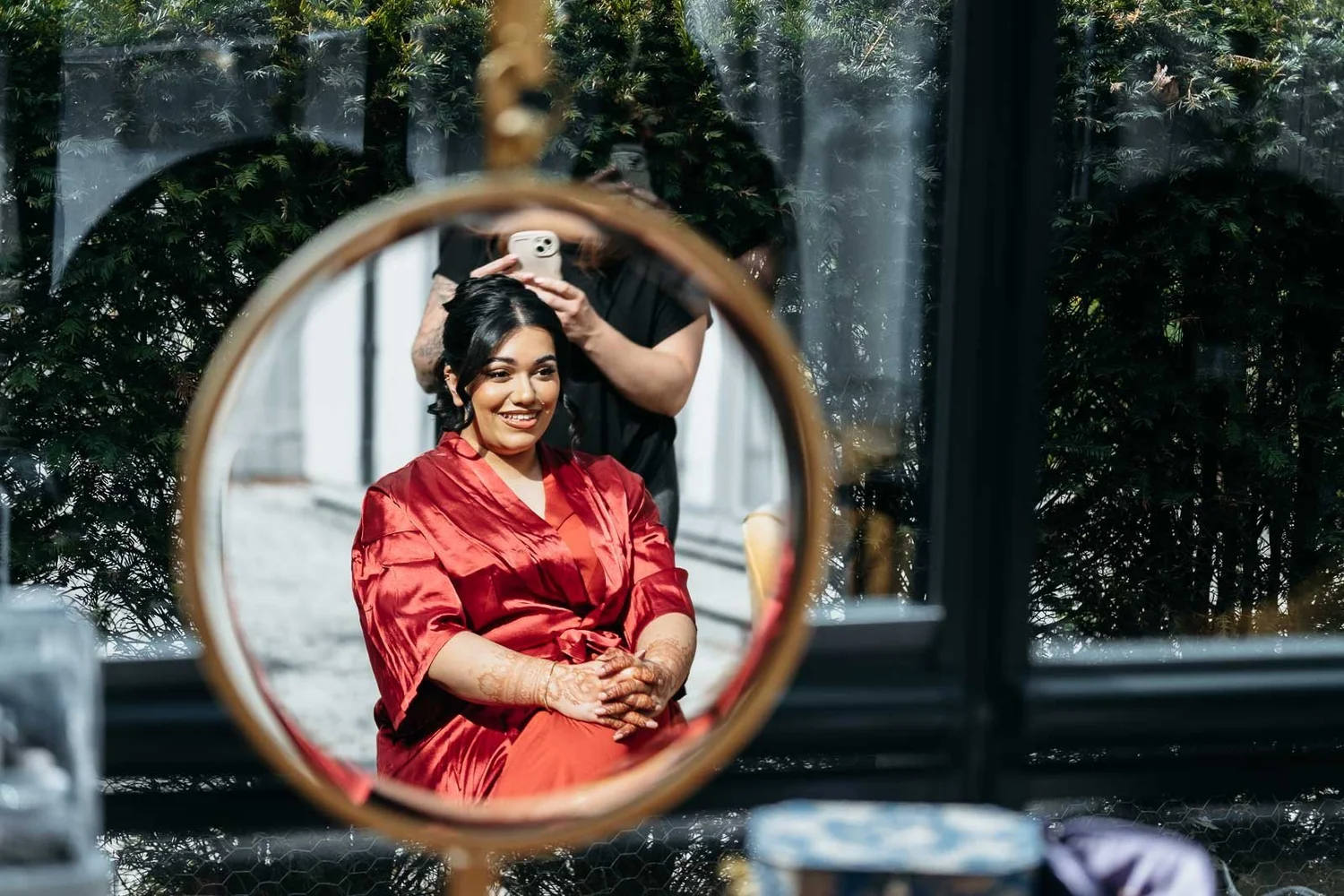 Bride reflected in a round mirror while getting ready at Lartington Hall
